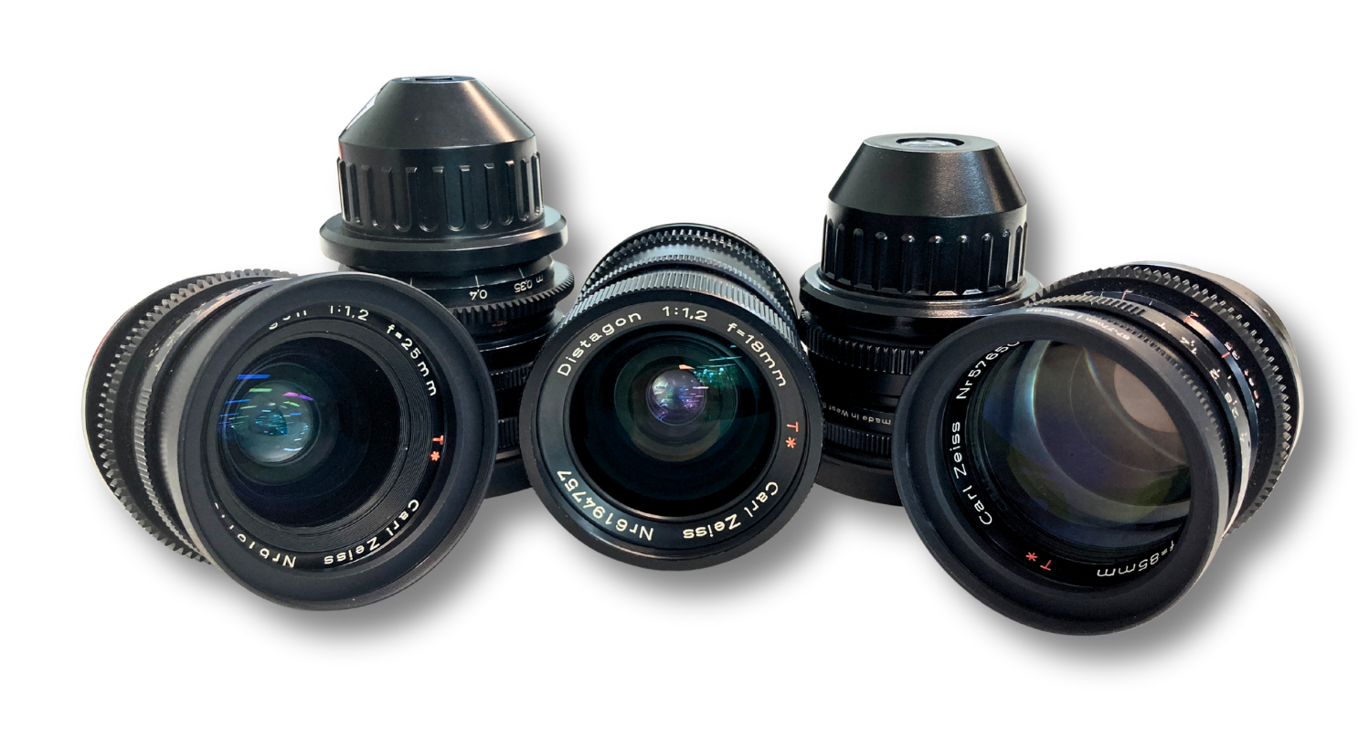 Several black camera lenses, some with hoods, arranged on a white surface.
