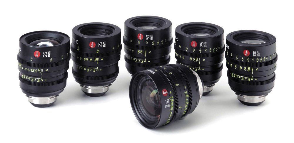 Five black camera lenses arranged on a white surface.