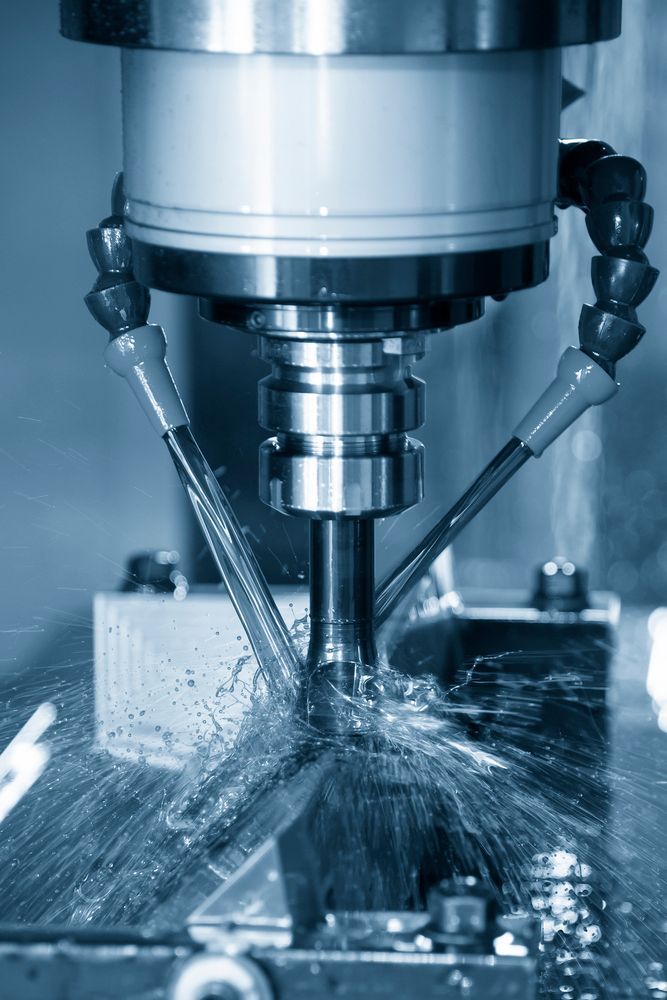 Fresadora CNC cortando metal con pulverización de refrigerante alrededor de la pieza de trabajo.