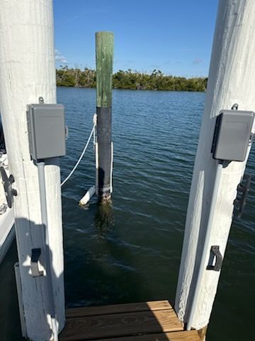 Dock opening with water view, white posts, and a green marker post in the center