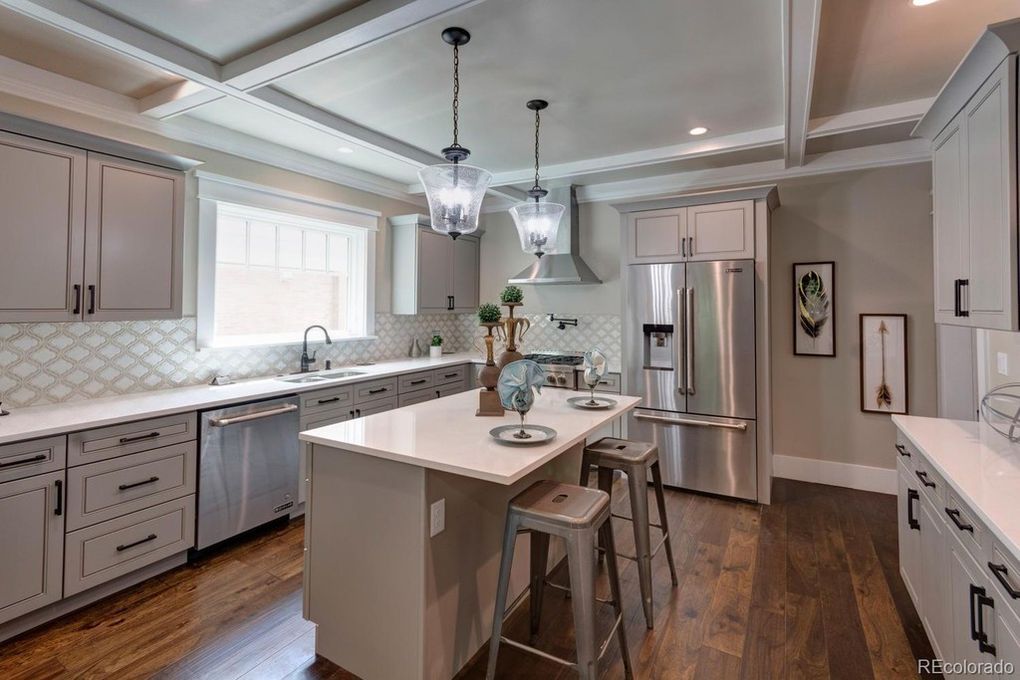 Gray kitchen with a white countertop island, stainless steel appliances, and dark wood flooring.
