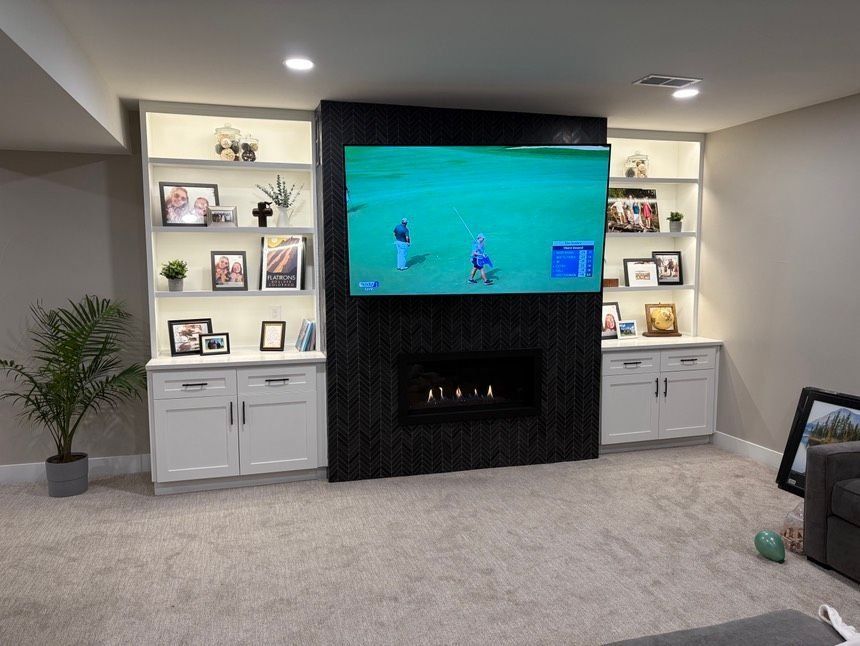 Living room with built-in shelves, fireplace, and TV displaying golf.