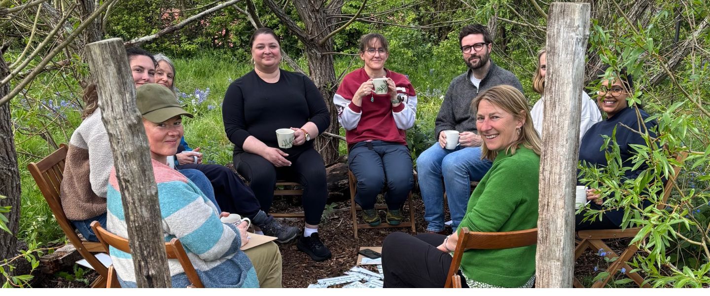 A group of mental health practitioners  outside in a circle with cups of tea
