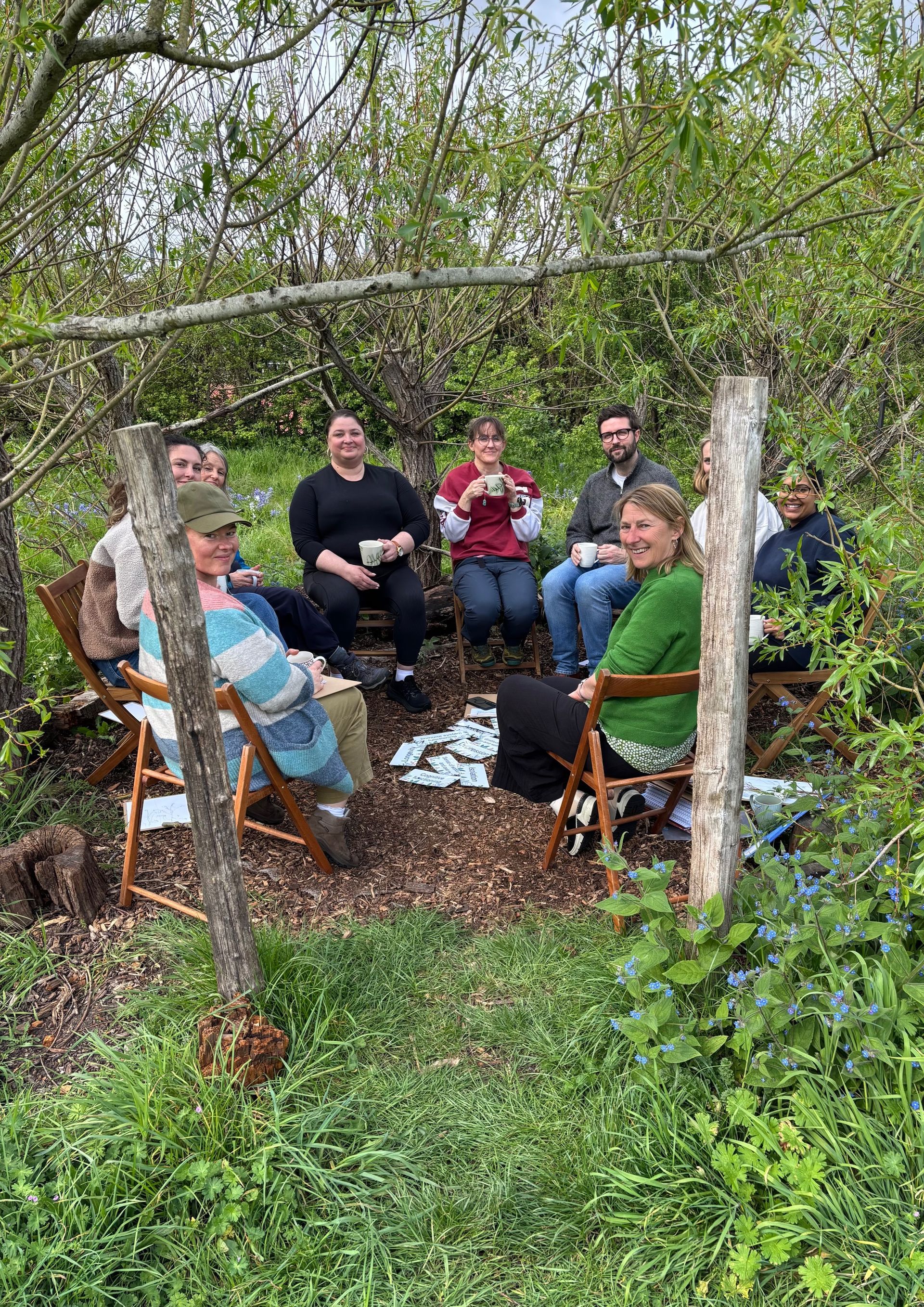 A group of practitioners sat in a circle outside drinking tea