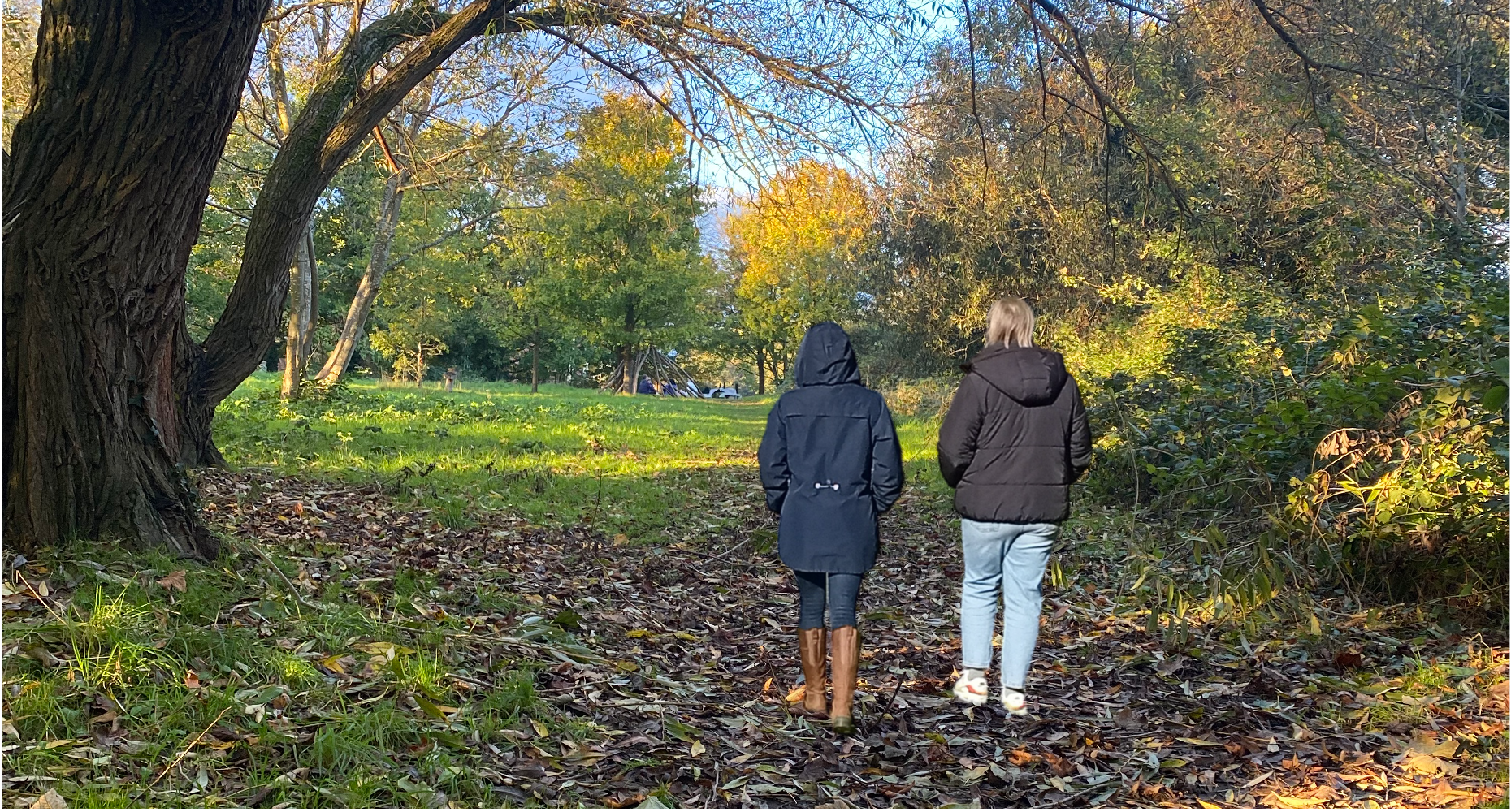 Two people walking along a wooded path together