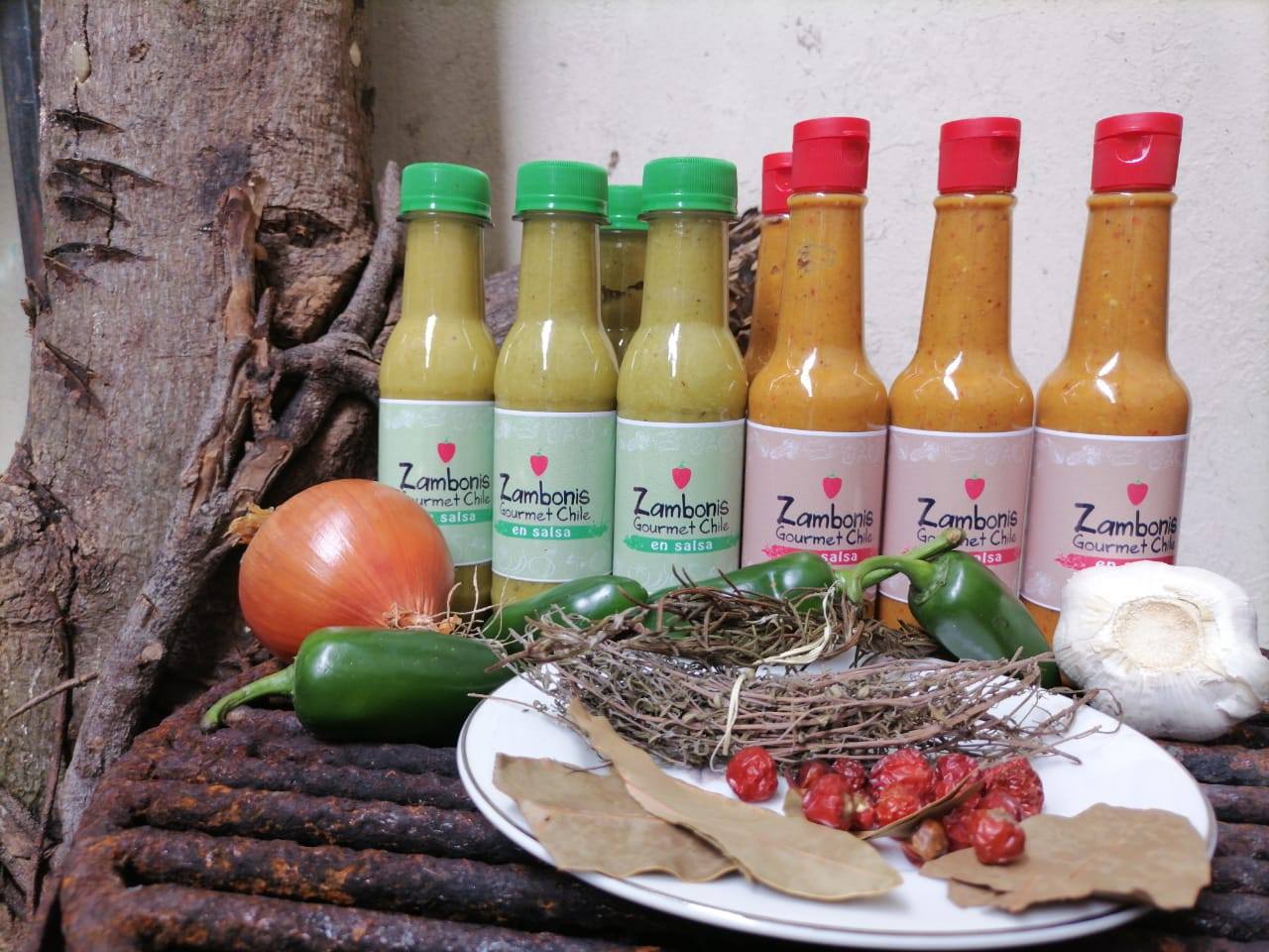 Assorted condiments and spices arranged with vegetables and herbs on a table outdoors.