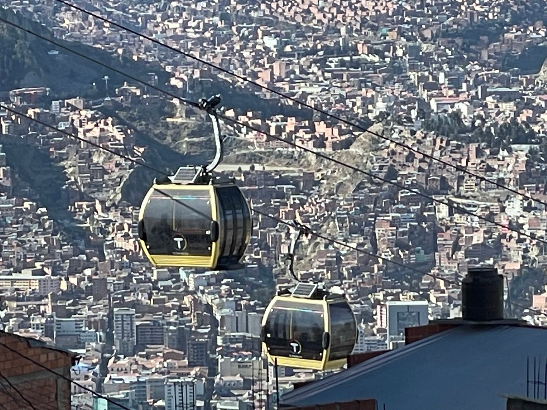 Two cable cars descending over a sprawling hillside city skyline