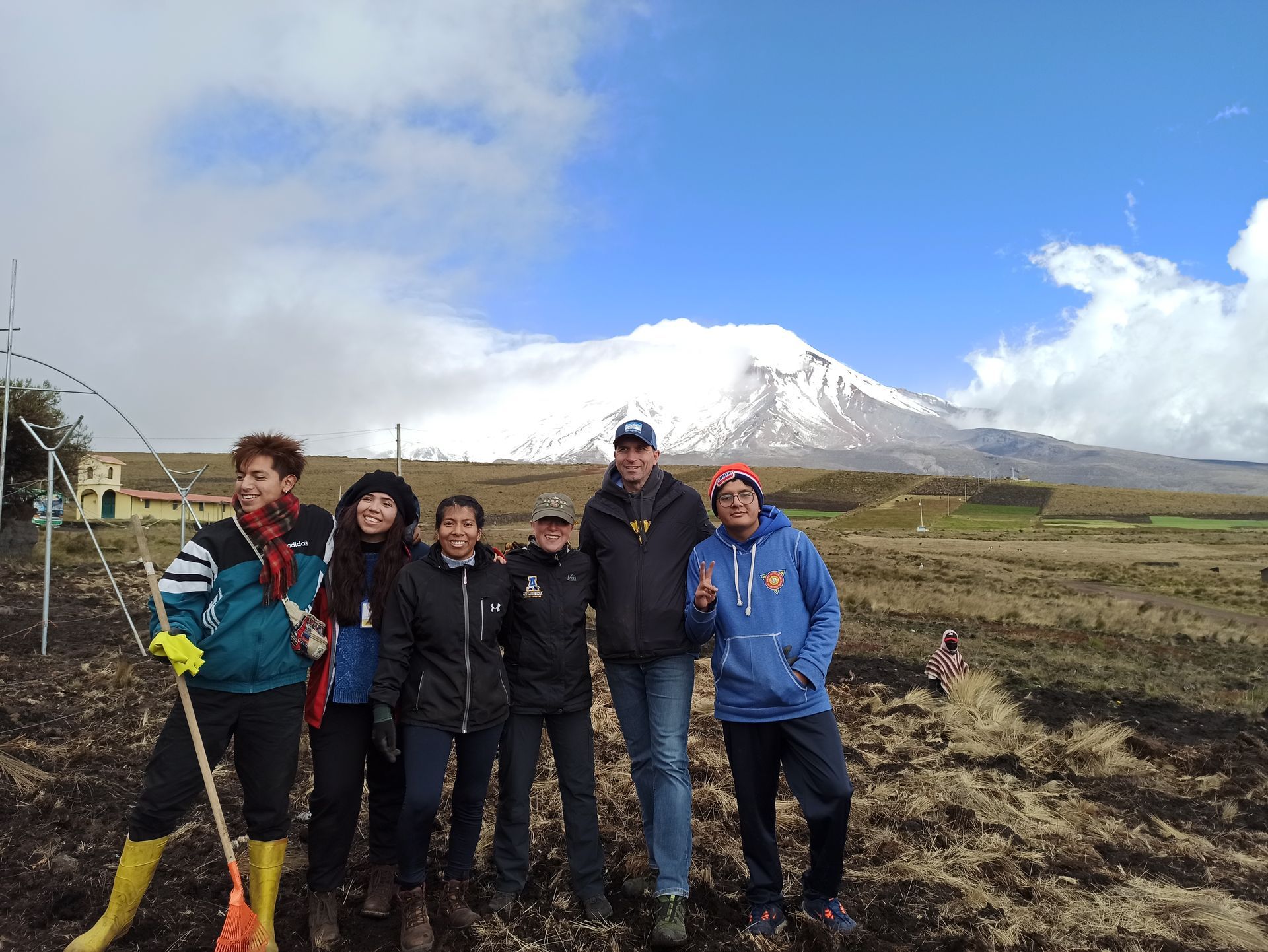 Five people posing in a field with snow-capped Mount Fuji in the background