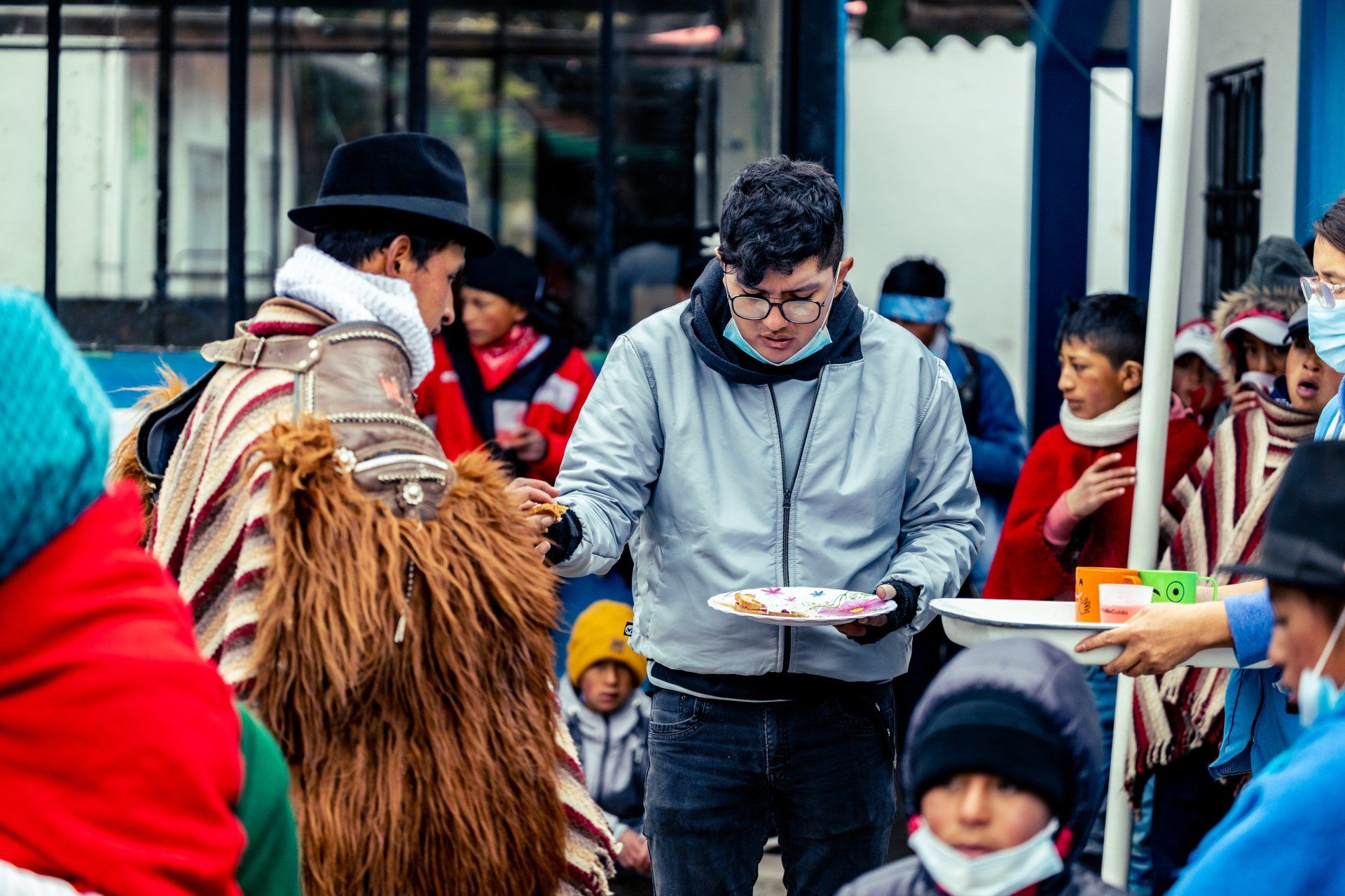 People in winter coats sharing food at an outdoor market or festival