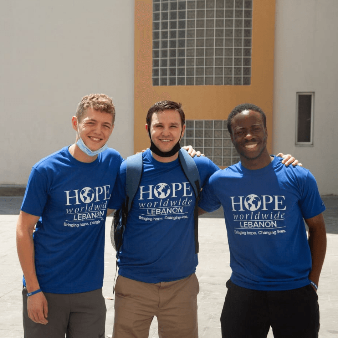 Three people in blue “Hope” T-shirts standing together and smiling outdoors