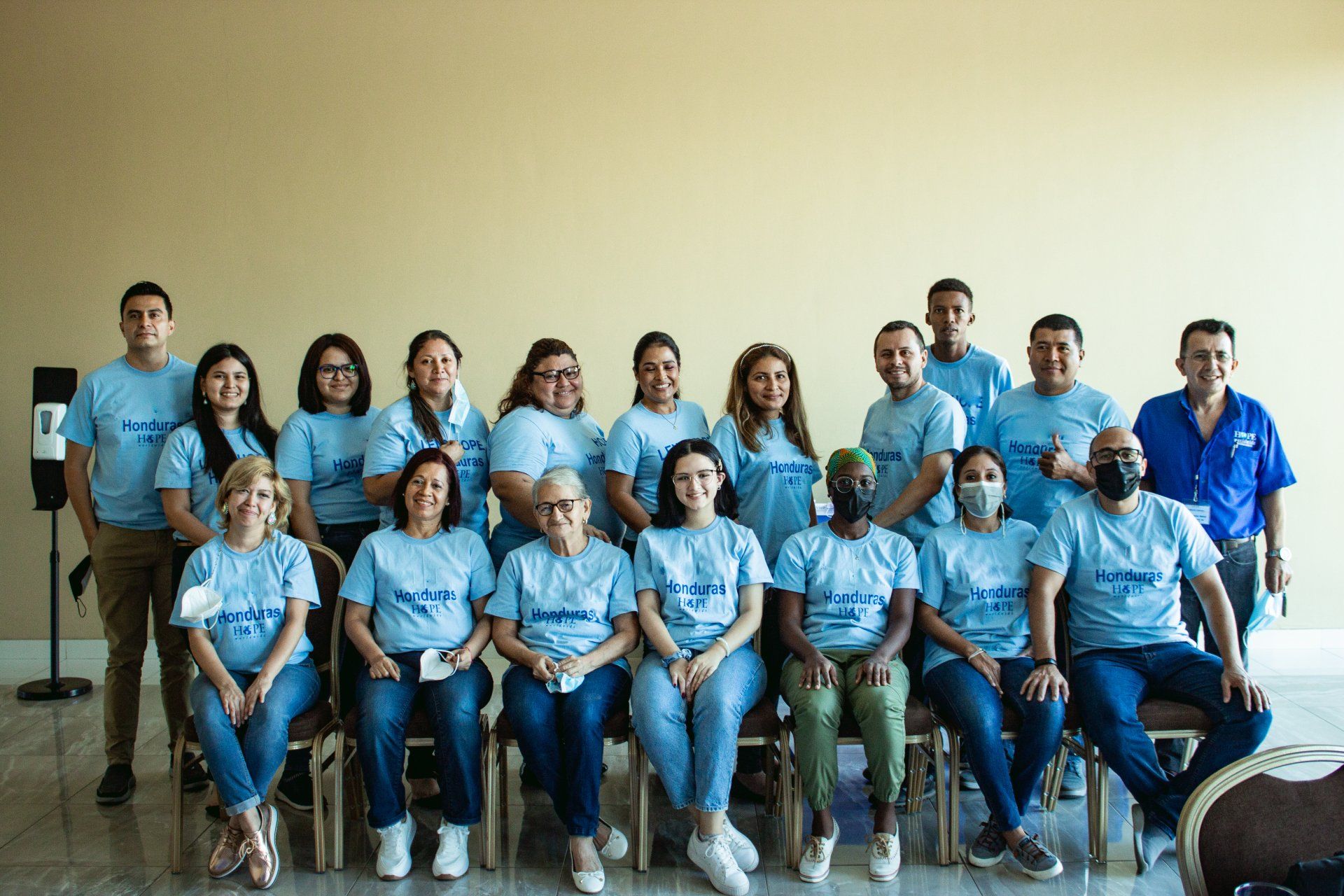 Group of people in matching blue shirts posing indoors for a team photo