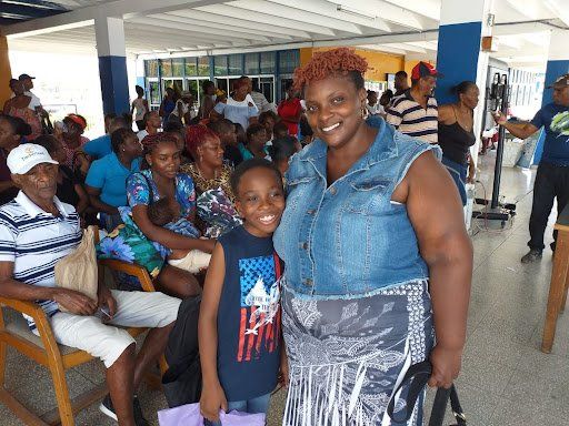 Woman and child smiling at an indoor community gathering with seated attendees in the background