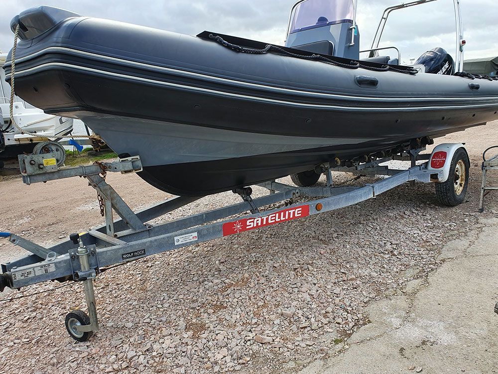 a boat is sitting on a trailer on a gravel road .