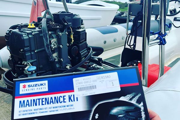 a person is holding a maintenance kit in front of a boat engine .
