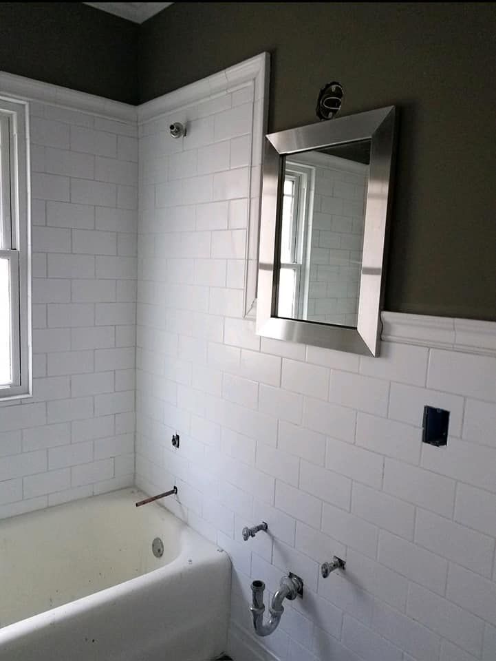 A bathroom with a tub and a mirror on the wall