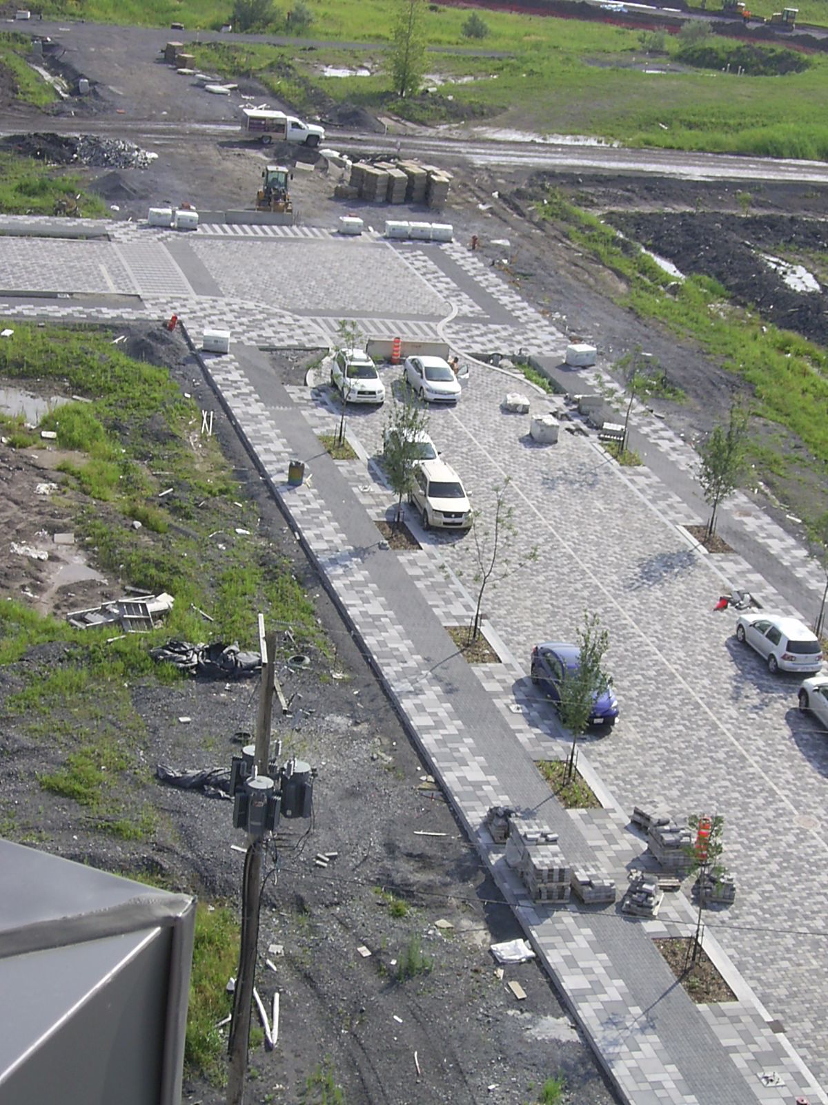 Vue aérienne d'une rue en construction avec des voitures garées et des pavés.