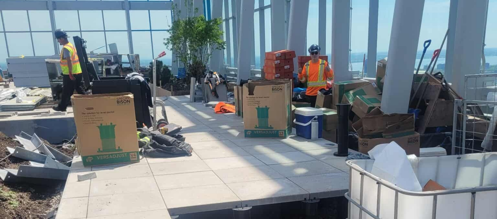 Chantier de construction avec ouvriers, cartons et matériaux sur un toit offrant une vue sur la ville.