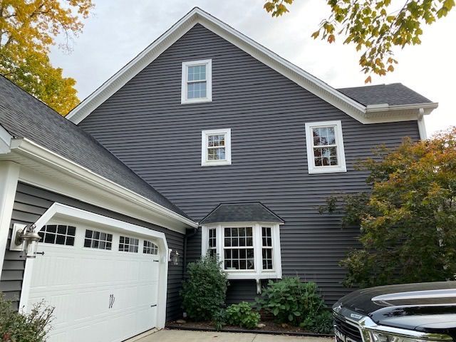 A large gray house with a white garage door and a black truck parked in front of it.
