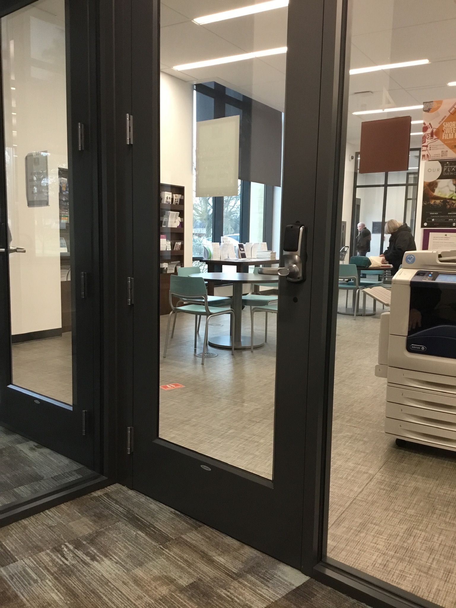 Glass doors open into a bright office with desks and chairs inside.