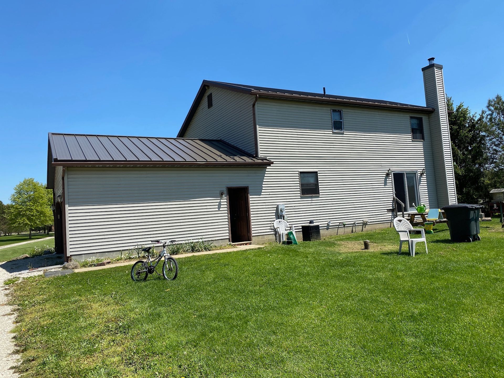A bicycle is parked in the grass in front of a house.