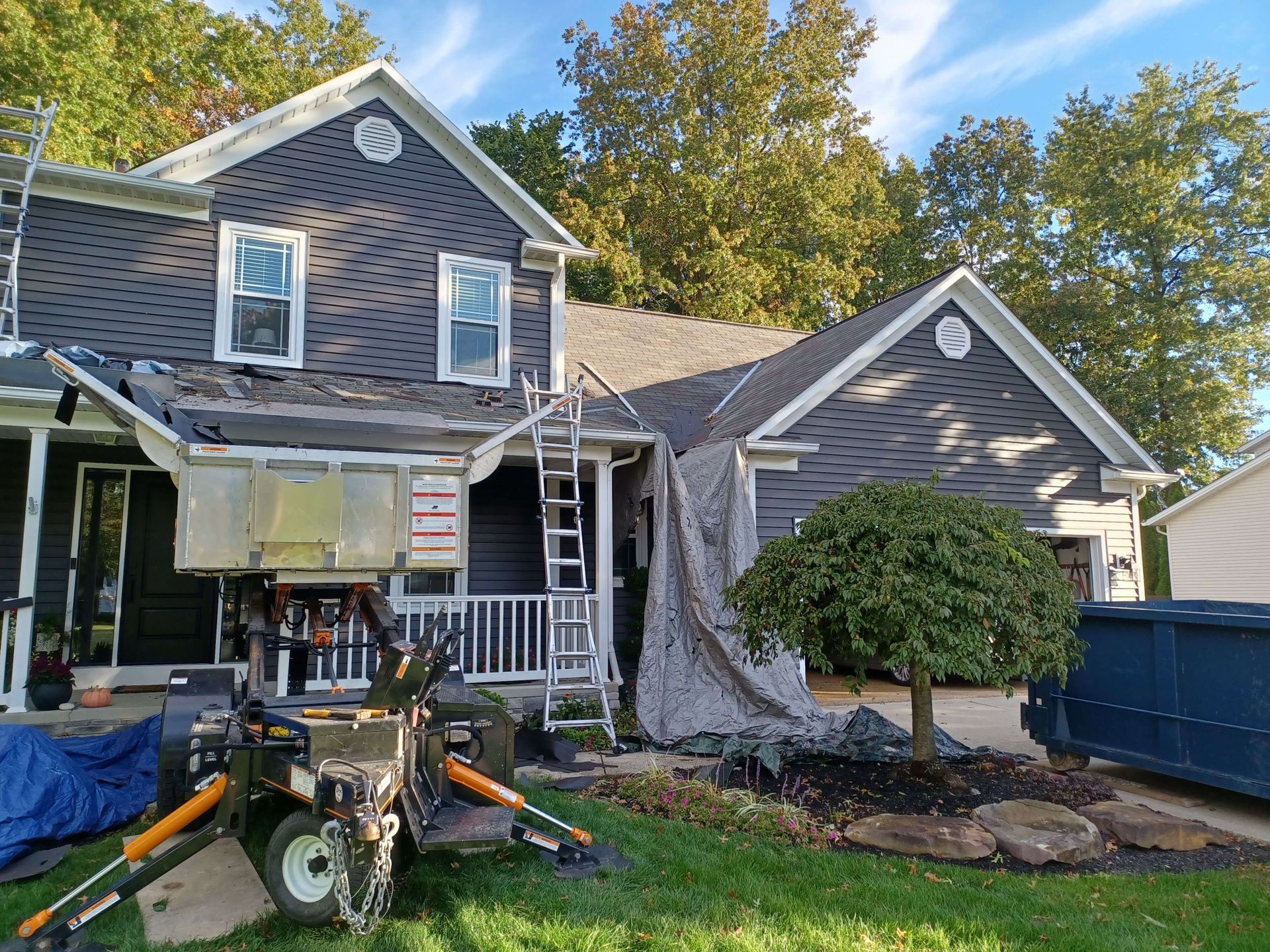 House exterior with workers using a lift and equipment during roof or siding repair