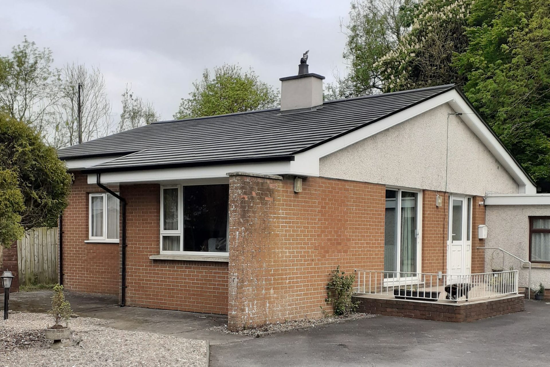 The same bungalow after roof replacement, with new slate, white fascia, soffit and seamless guttering