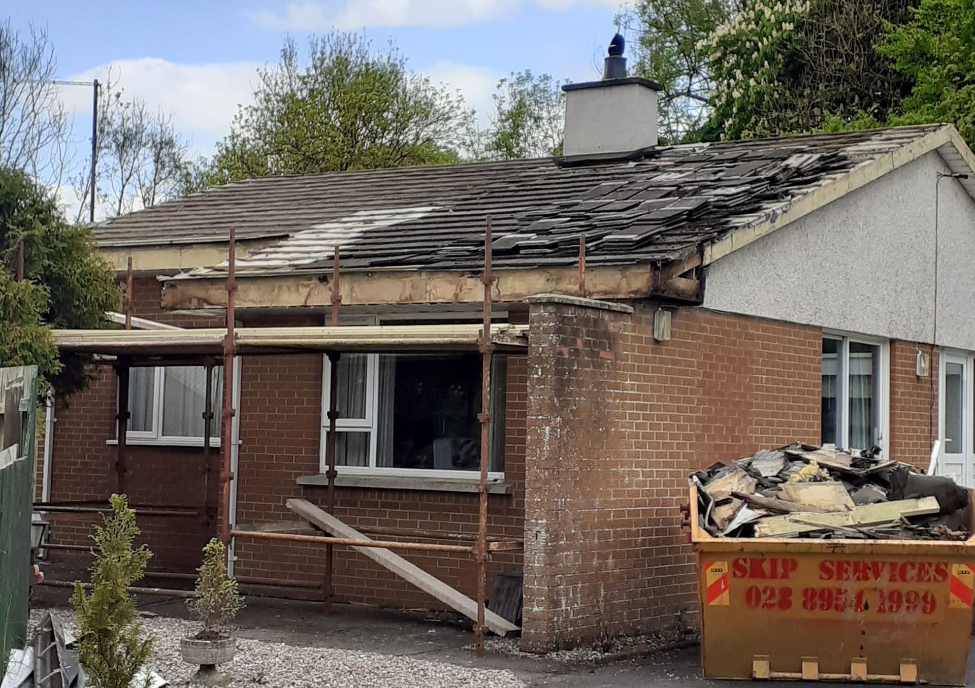 Bungalow roof before replacement, with old slates stripped back to the timbers and scaffolding in place