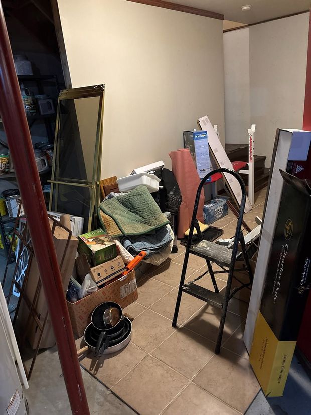 Cluttered room with chairs, boxes, bags, and a mirror leaning against the wall.
