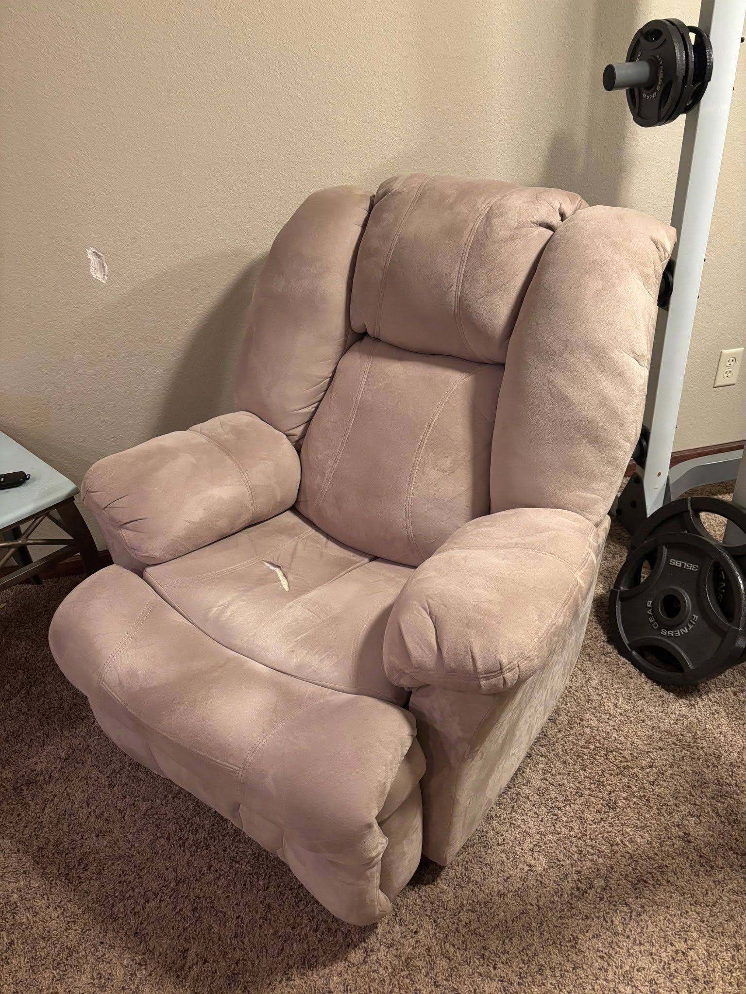 Light pink cushioned recliner chair on carpet in a room corner