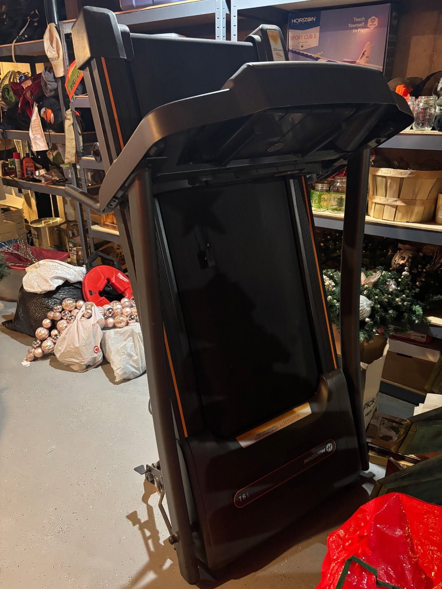 Tilted black treadmill in a store aisle, with holiday decorations and shelves in the background