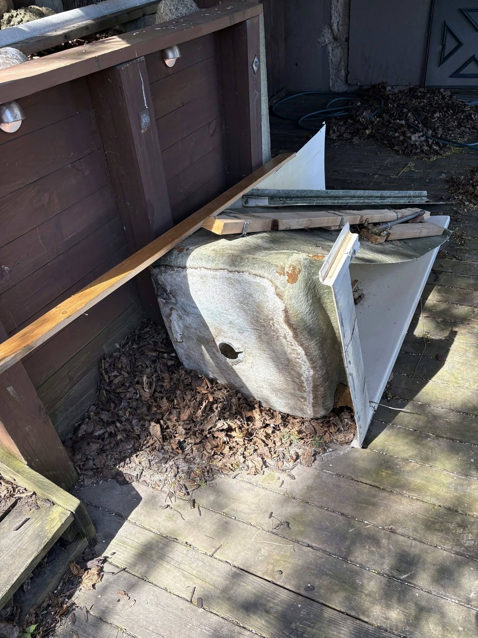 Overturned patio chair on wooden deck beside a fence, with debris scattered around.