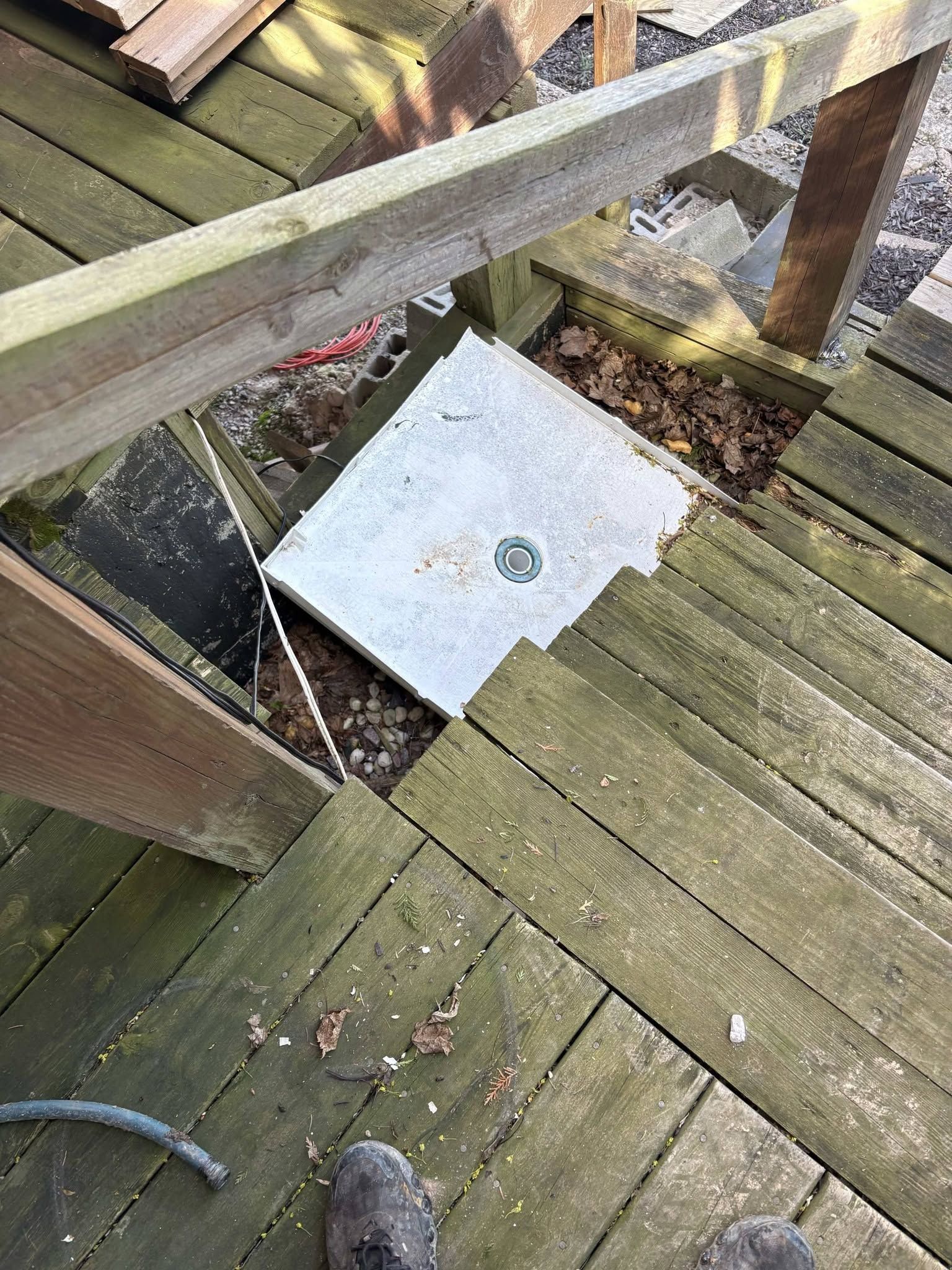 Wooden deck with a broken section revealing water below and a white square panel on the opening
