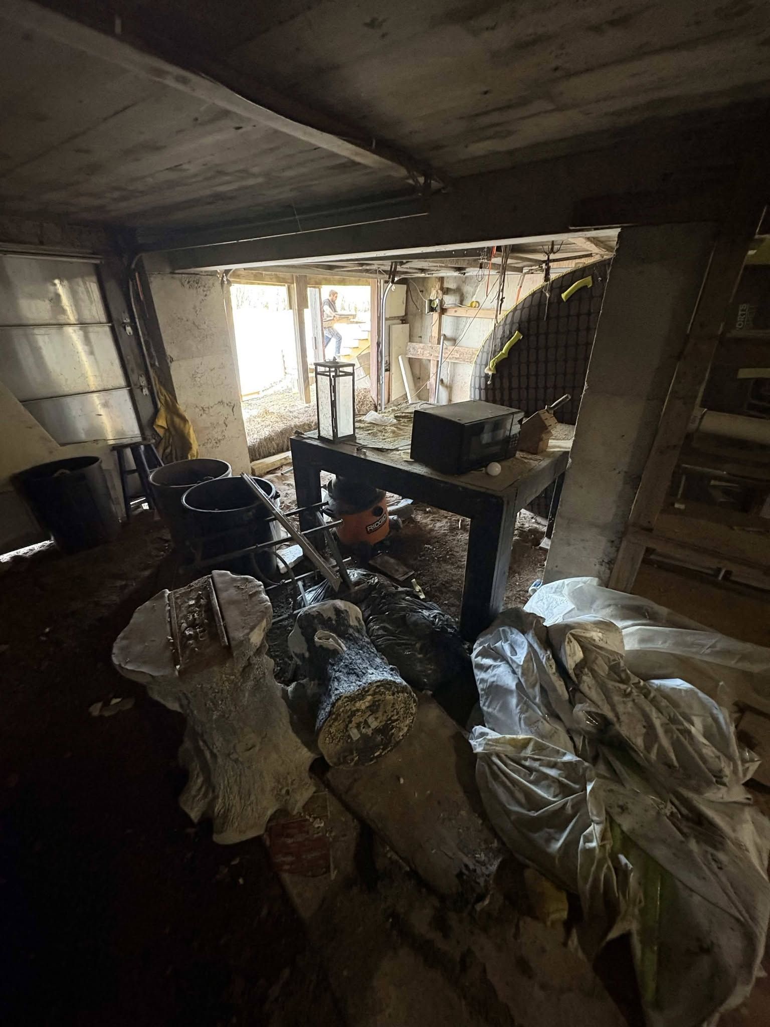 Damaged room with debris, burned walls, and a window letting in daylight