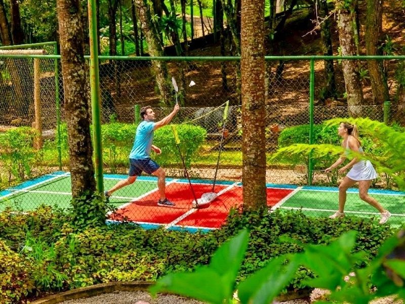 Um buffet de café da manhã com diversos tipos de pães, bolos, uma fruteira com abacaxi e um arranjo floral como centro de mesa.