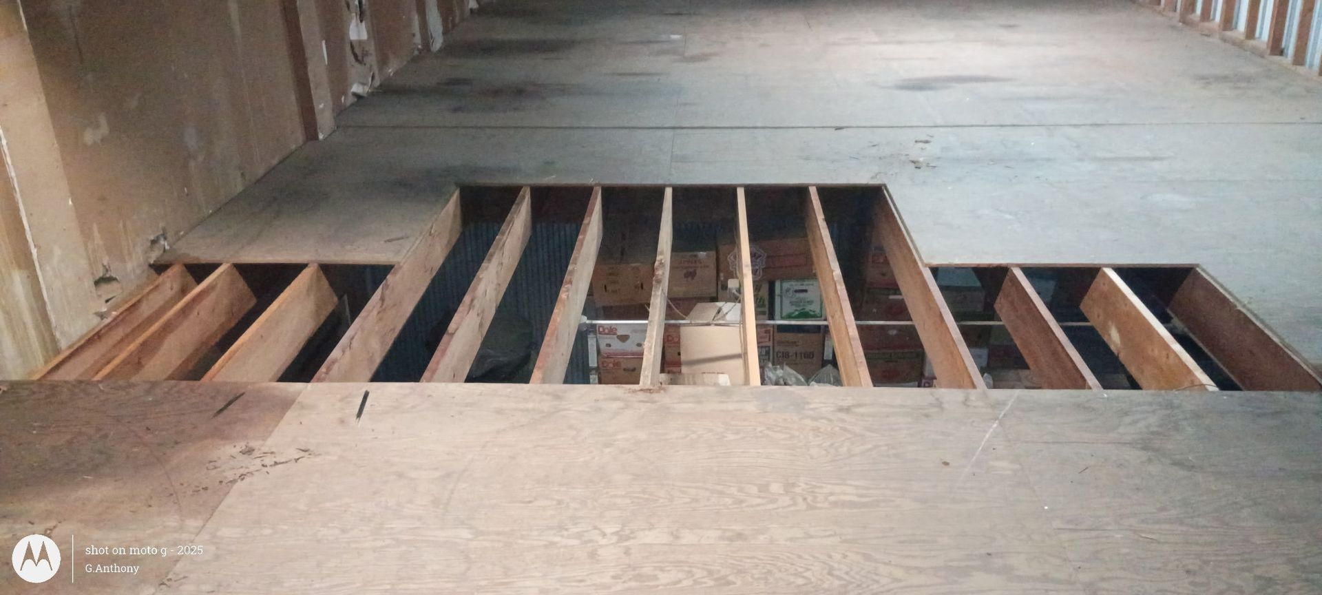 Open floor vent with exposed wooden slats and a small patch of greenery in the center