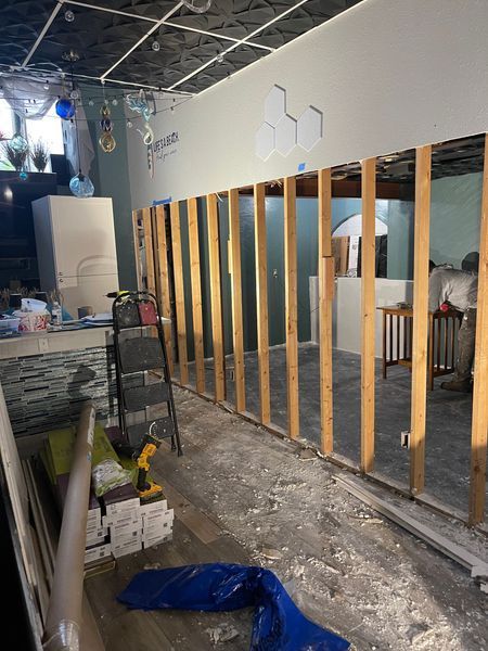 Construction site: wall studs, drywall partly installed. Tools and debris scattered. Interior setting.