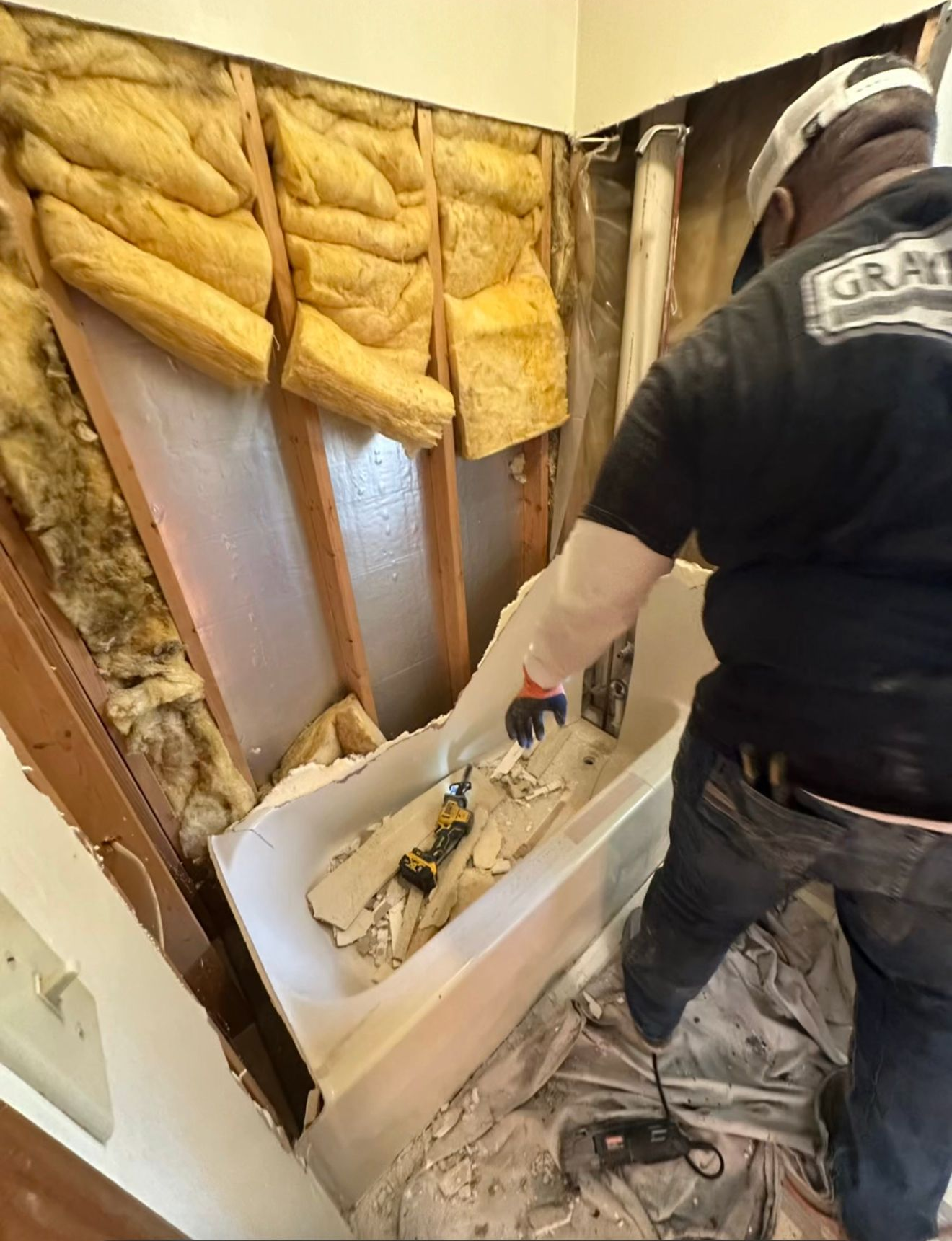 Worker removing insulation from a wall cavity during home renovation