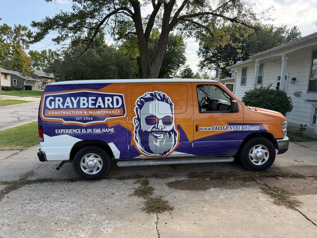 Graybeard service van parked in a driveway, orange and purple with a bearded logo and house-call contact info.