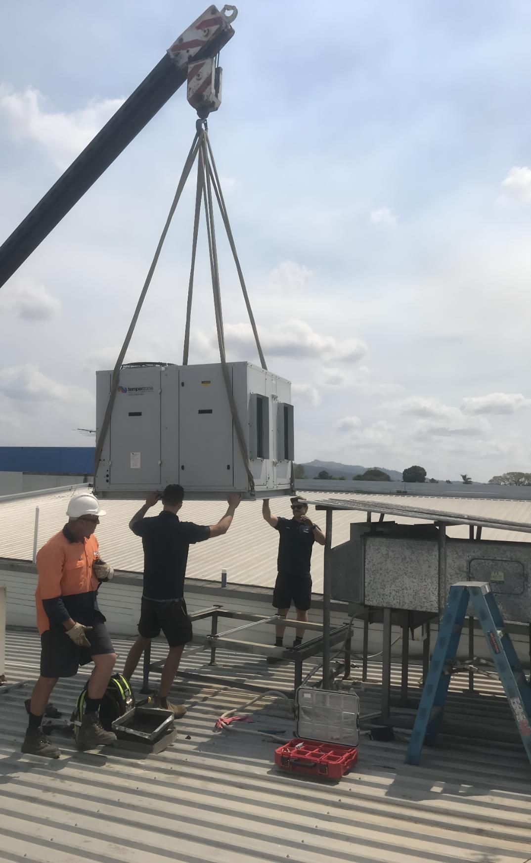 Group of Men Are Working on a Roof With a Crane — Brenden Wilson Electrical in Caloundra, QLD