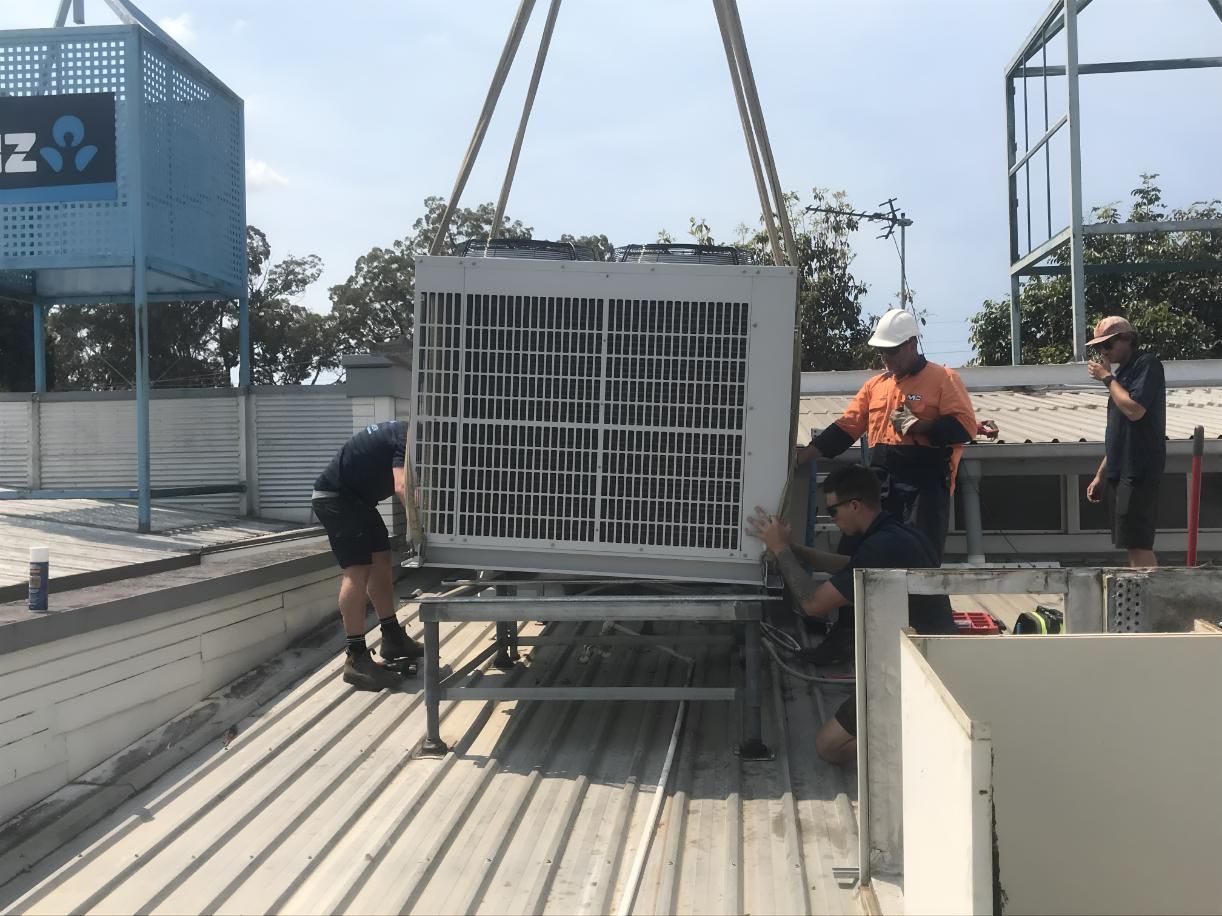 Group of Men Are Working on a Large Air Conditioner — Brenden Wilson Electrical in Beerwah, QLD