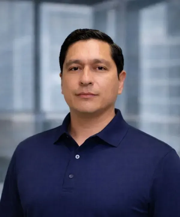 Portrait of a person in a navy polo shirt standing before a blurred office background