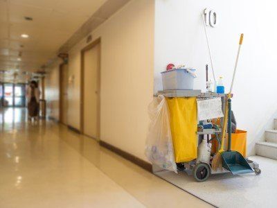 Hospital hallway with a janitor’s cleaning cart and mop bucket against the wall