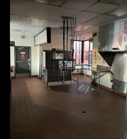 Empty commercial kitchen with tiled floor, metal counters, and a closed door in the back. Empty commercial kitchen with tiled floor, metal counters, and a closed door in the back.