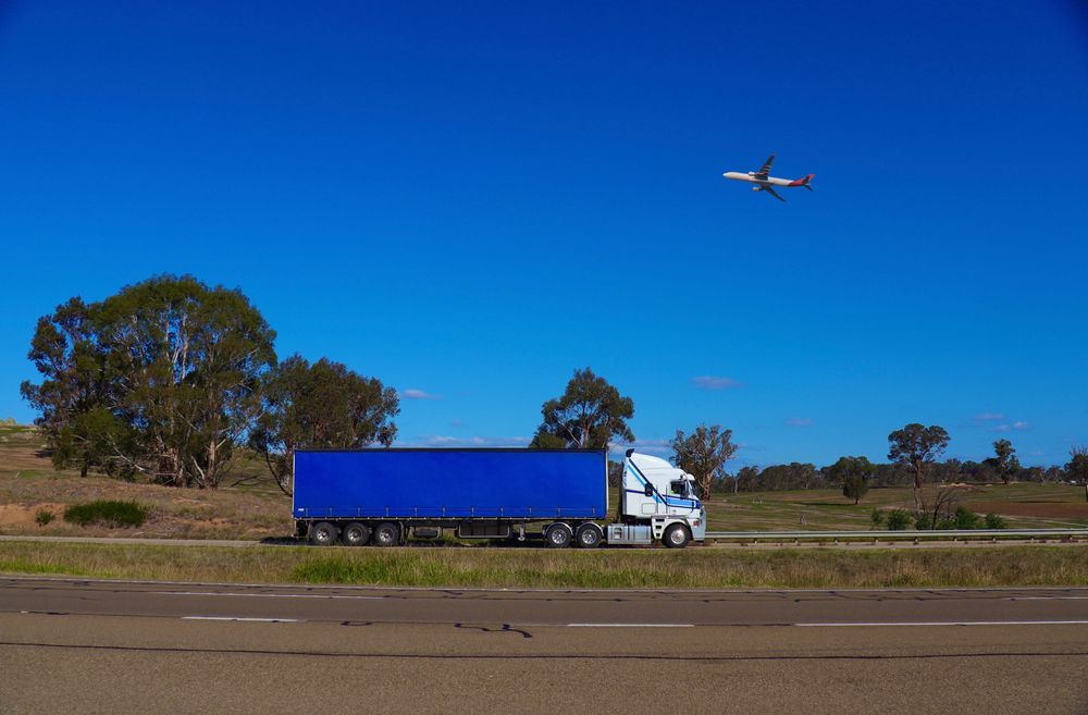 Blue Semi Truck Driving On A Rural Road Under A Clear Blue Sky — Southern Protein Systems in Glenquarry, NSW