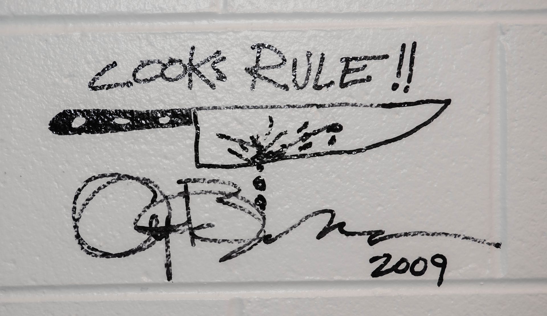 Black-and-white sketch with “COOKS RULE!!” handwritten above and a signature dated 2009, Anthony Bourdain