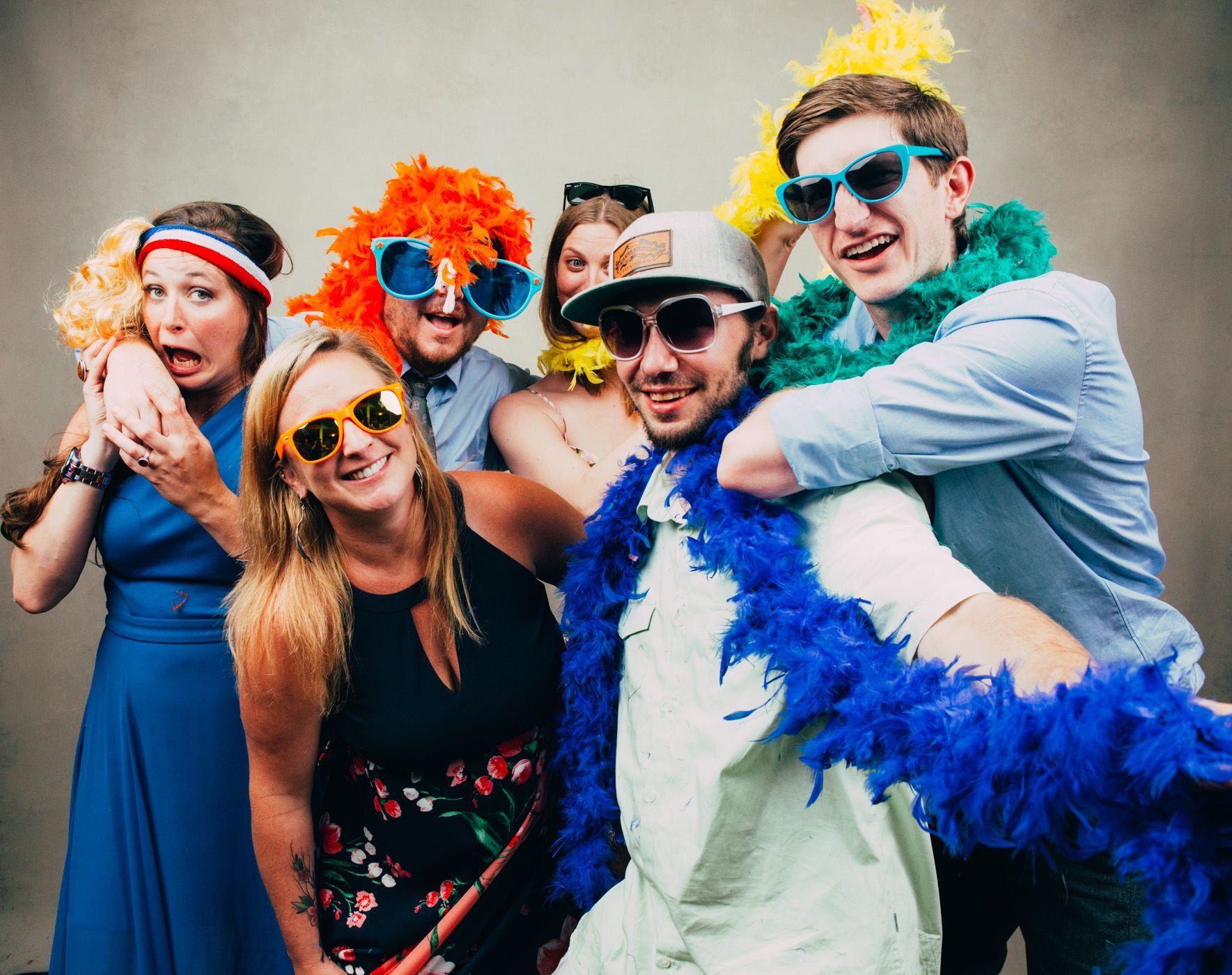 Five friends in colorful costumes and sunglasses posing playfully at a party.