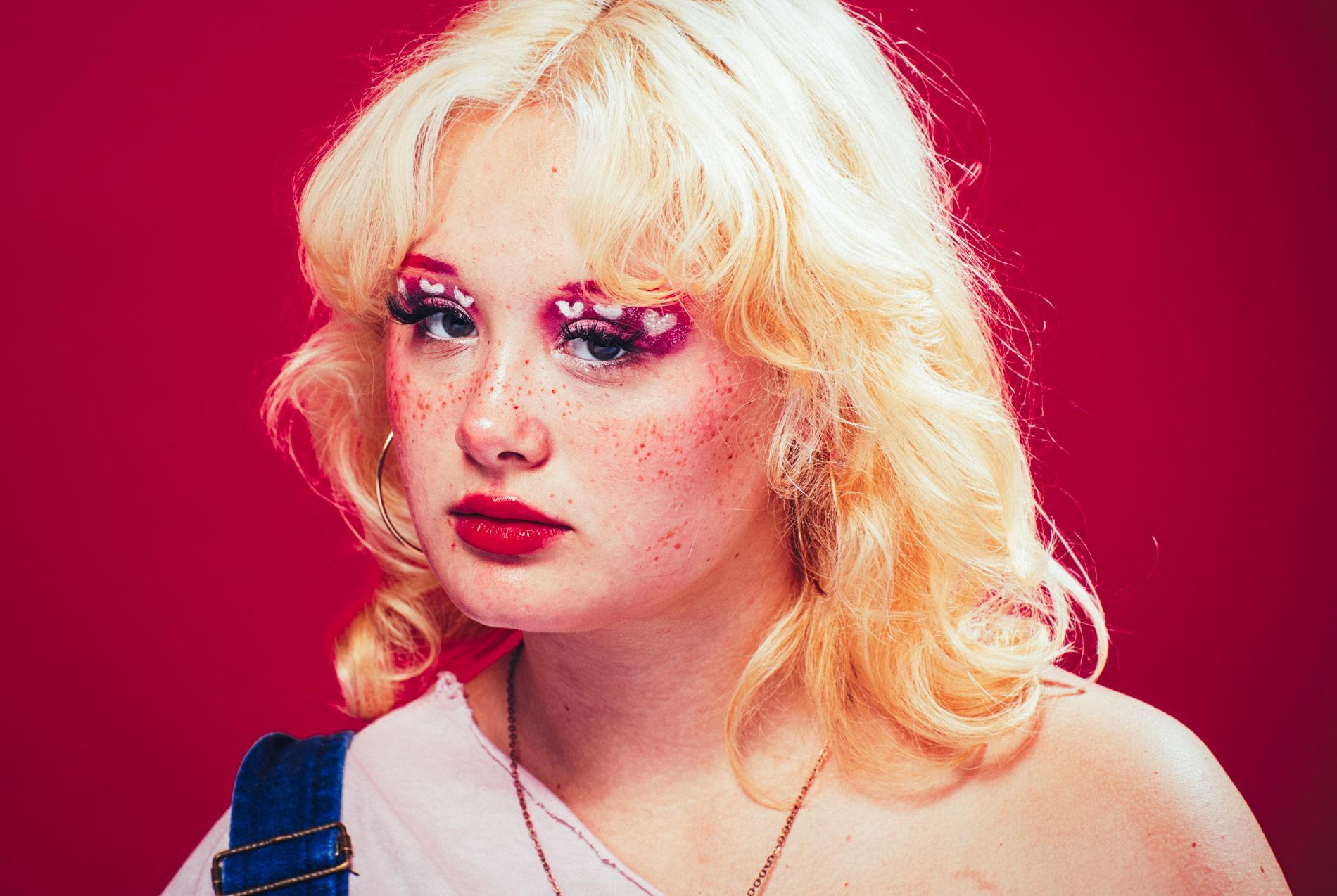 Blonde model posing against a bright pink background, portrait in studio by Asheville photographer Sandlin Gaither