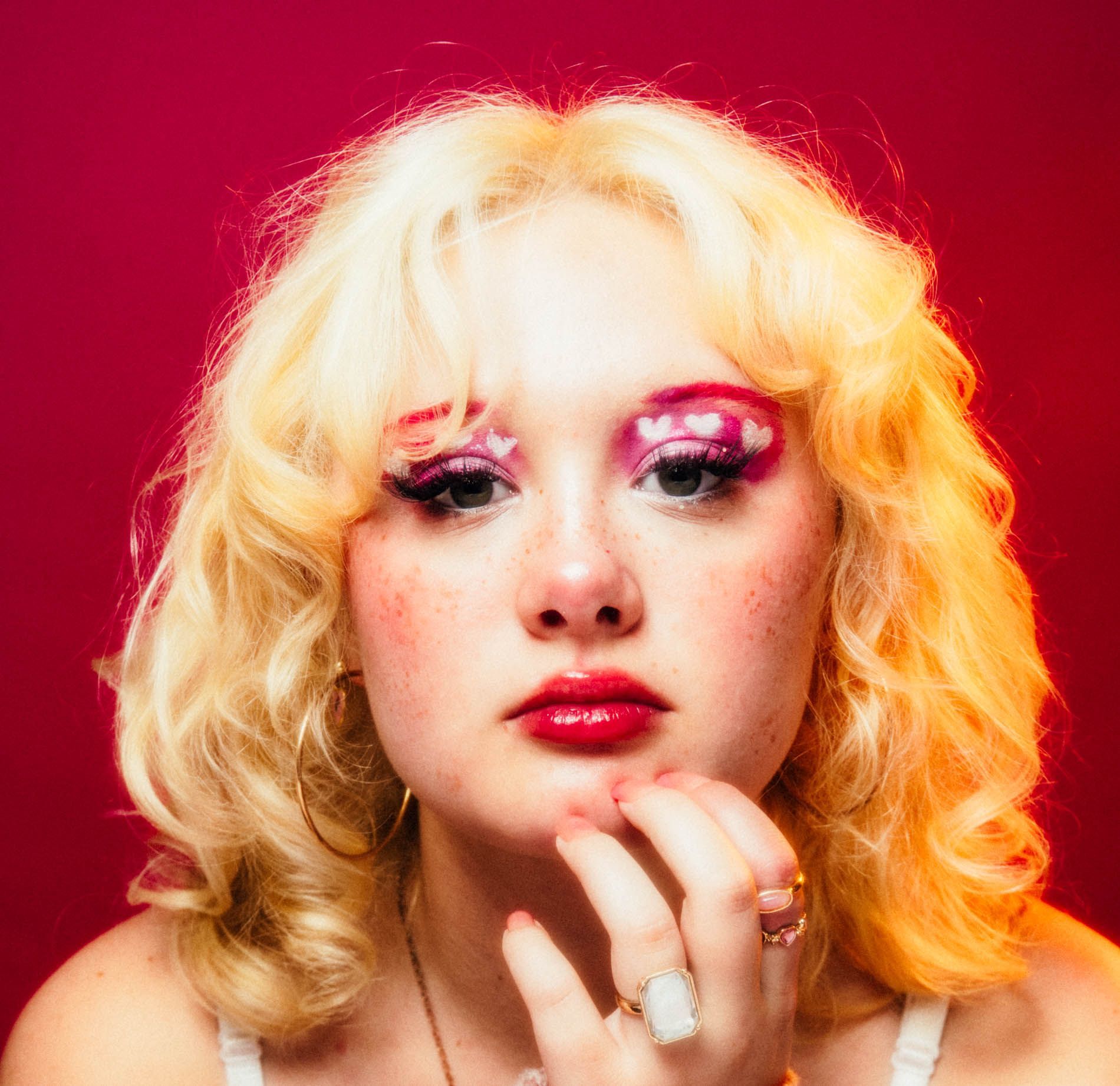 Blonde model posing against a bright pink background, portrait in studio by Asheville photographer Sandlin Gaither