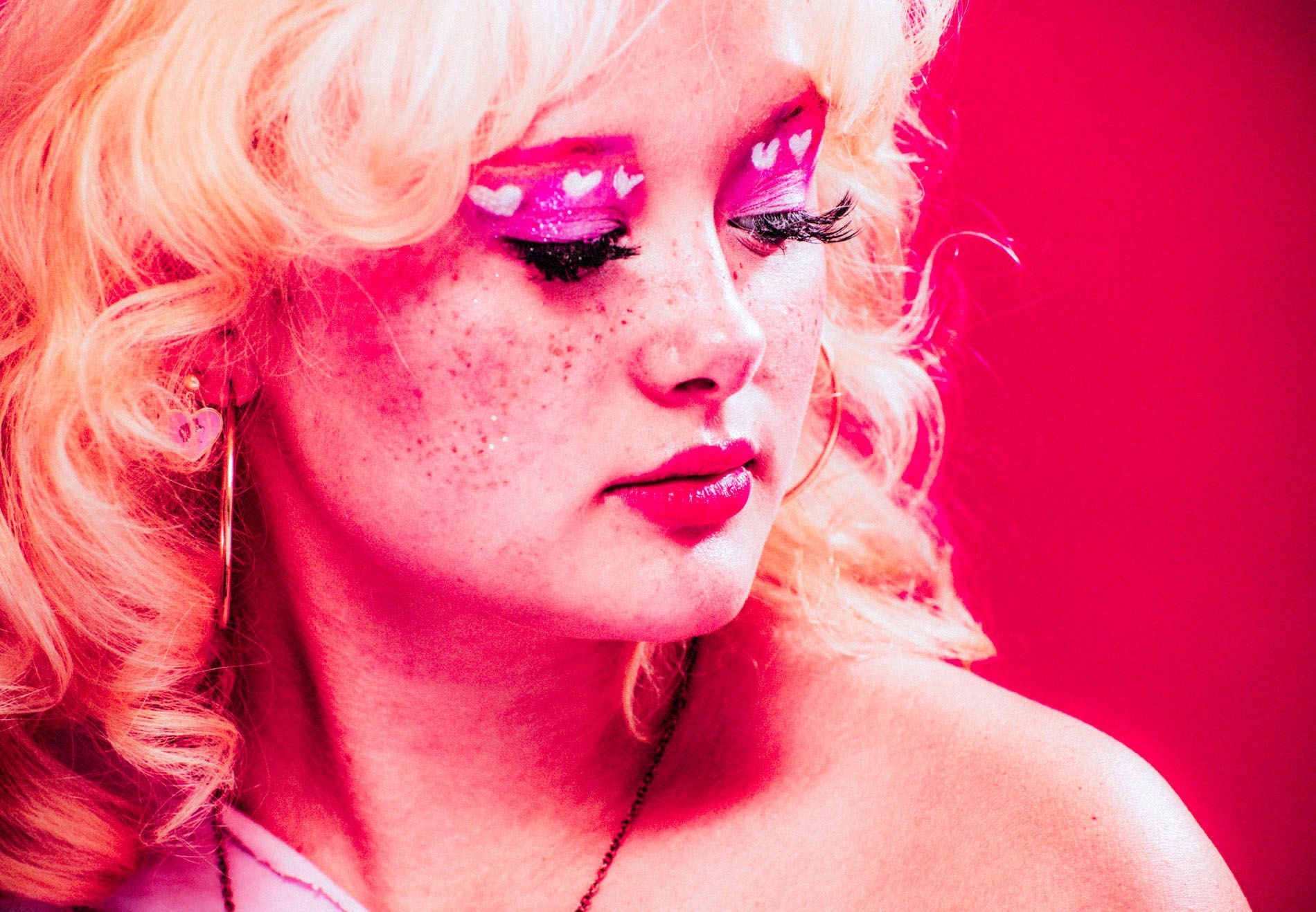 Blonde model posing against a bright pink background, portrait in studio by Asheville photographer Sandlin Gaither