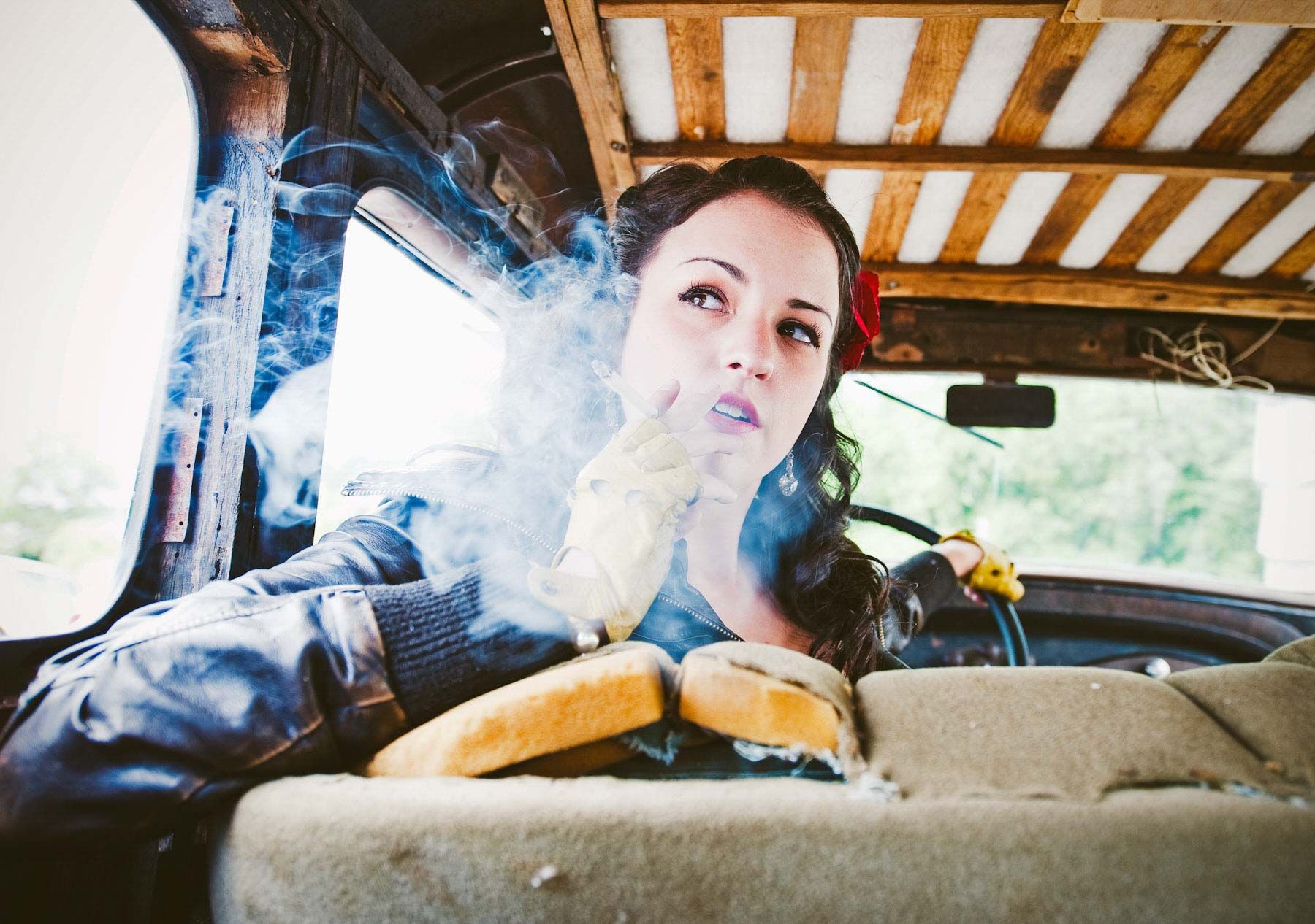Woman driving a van with smoke or steam around her hands, seen from the back seat.